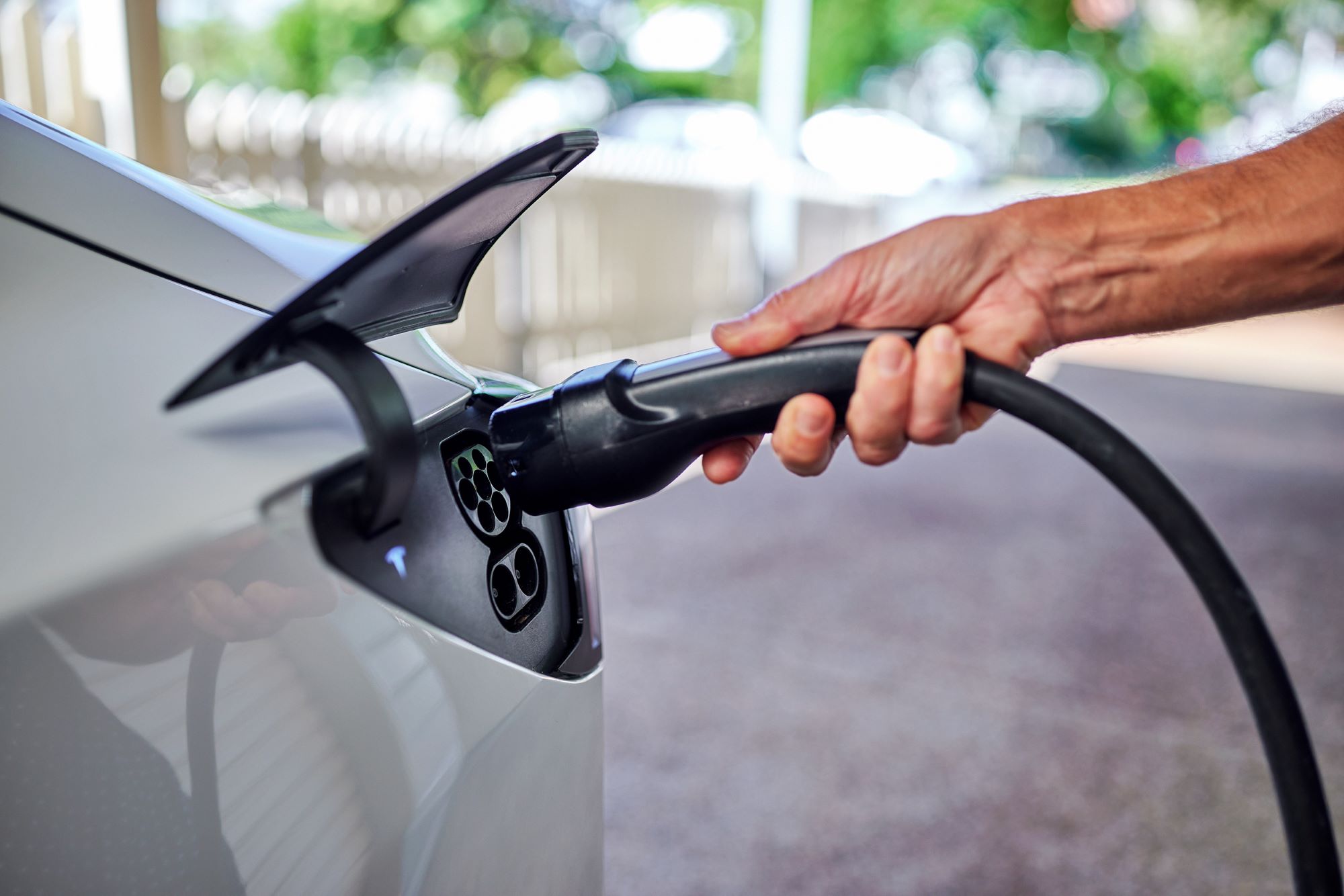 A person about to plug in their electric vehicle at home