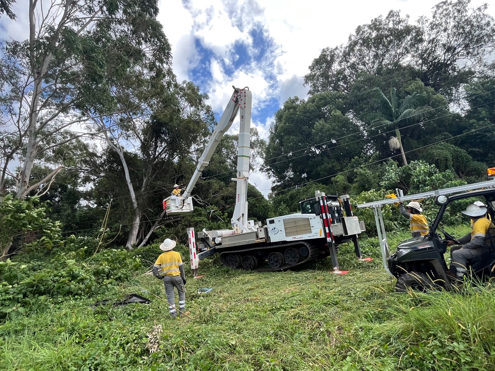 Crews using a tracked vehicle in bushland to work on powerlines