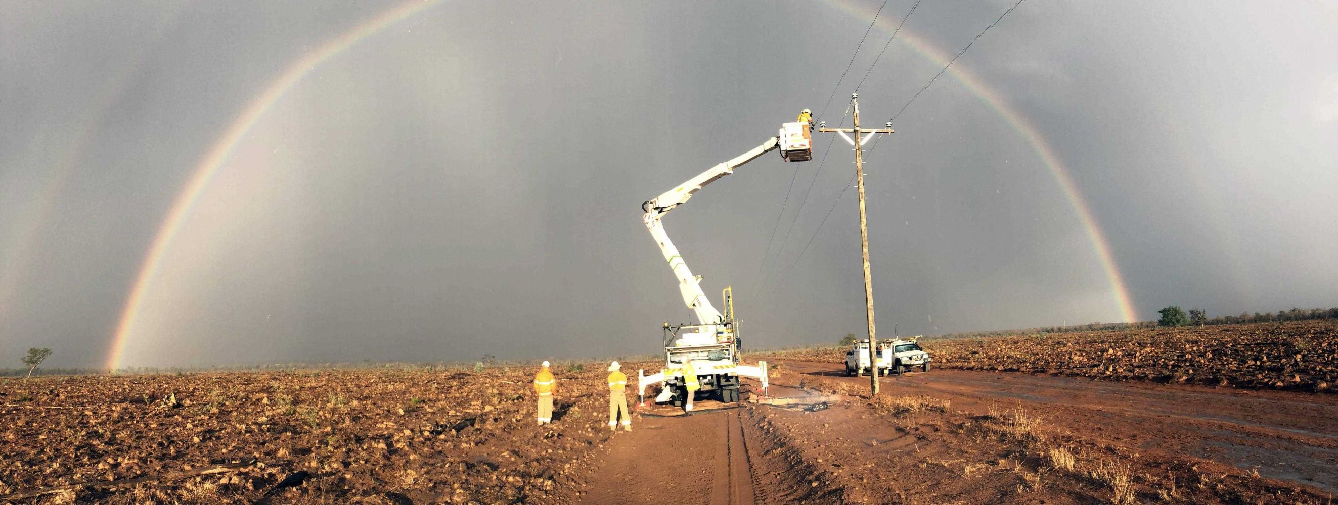Crews restoring power in a field with a rainbow in the background
