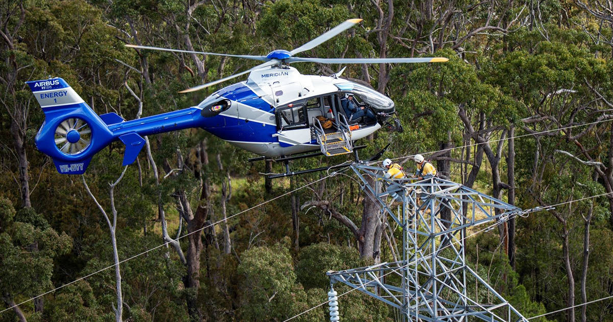 Helicopter assisting crews fixing powerlines on top of electricity tower