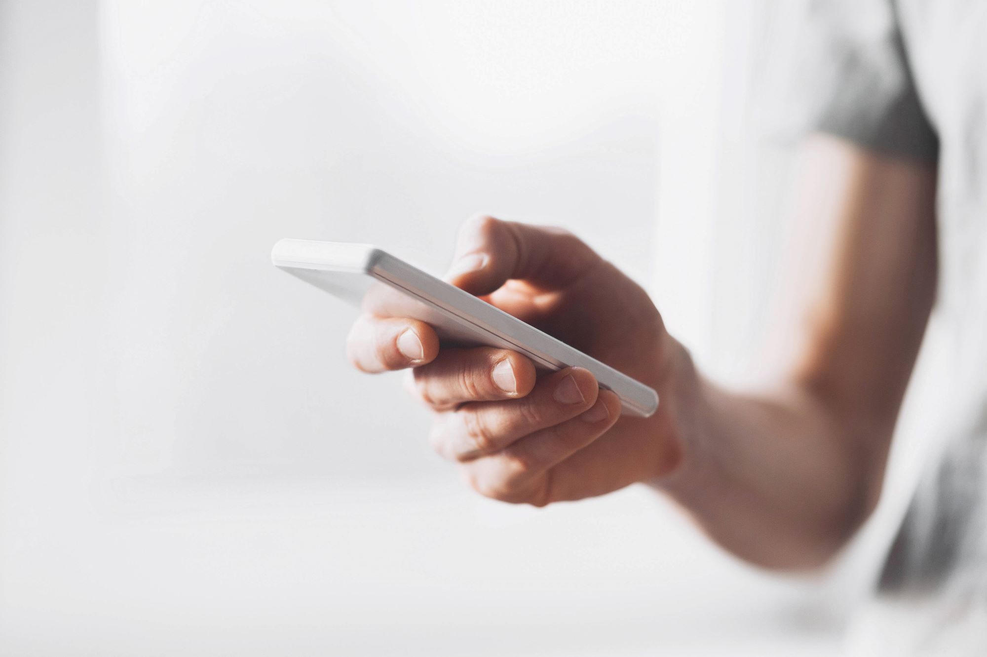 A person holding a smartphone with focus on hand