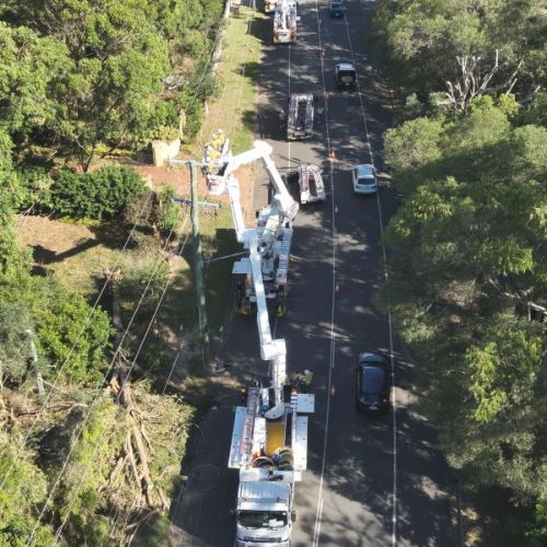 Aerial view of a number of work trucks with crew in cherry pickers working on powerlines