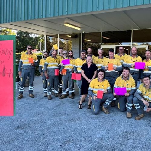 Group photo of crews at front of building holding signs from school students