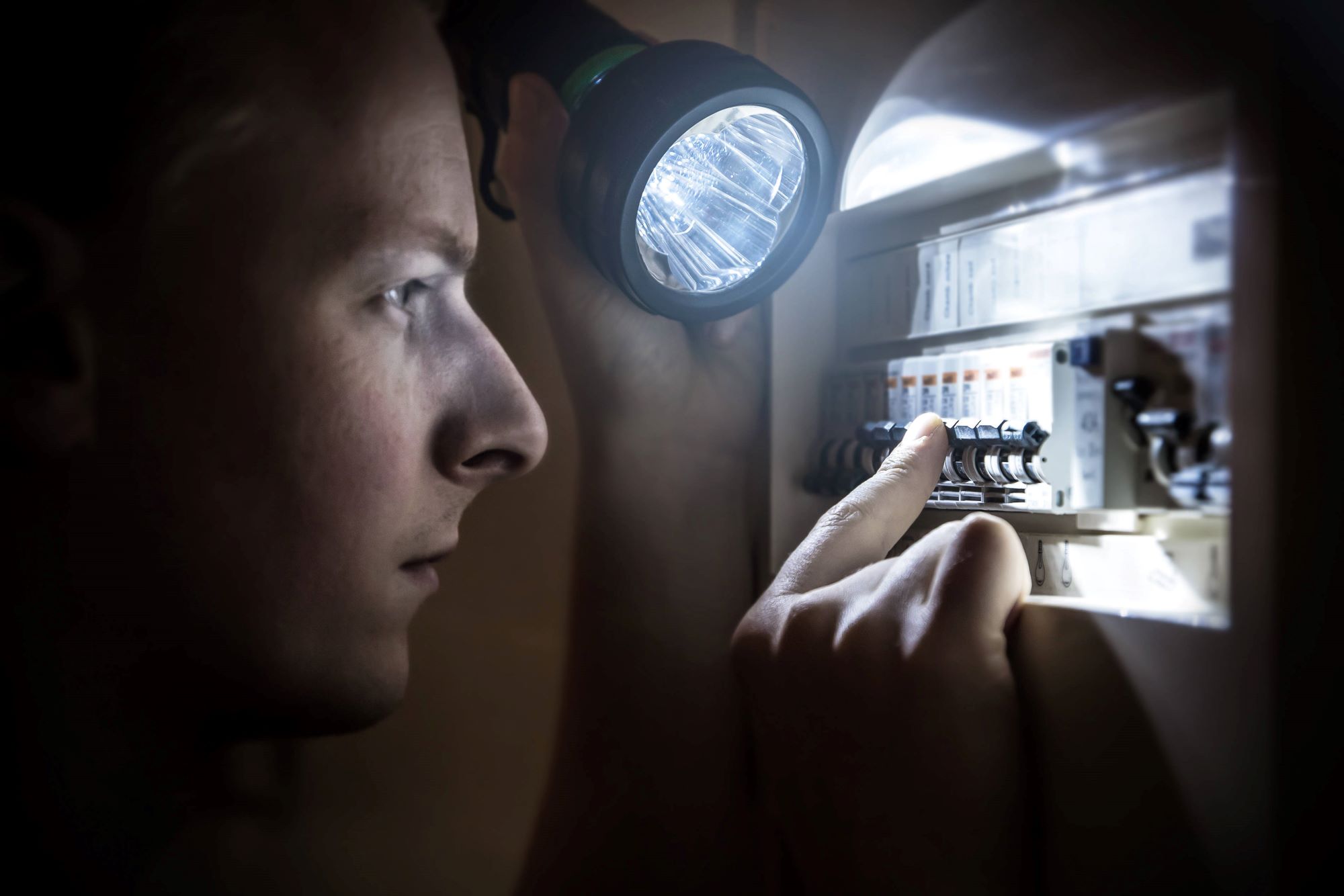 Man restoring power at the switchboard with a flashlight