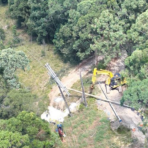 Aerial view of crane replacing power pole on ground in bushland
