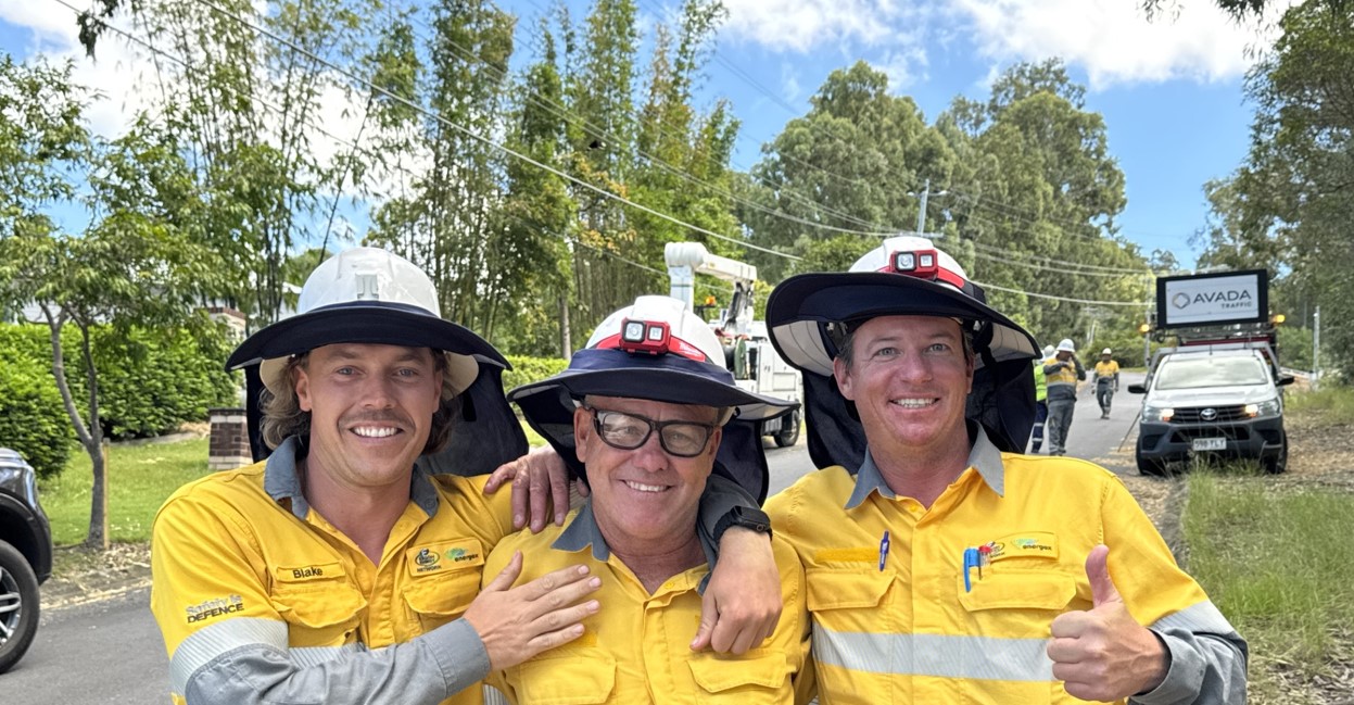 Three crew members together for group photo in the middle of the road