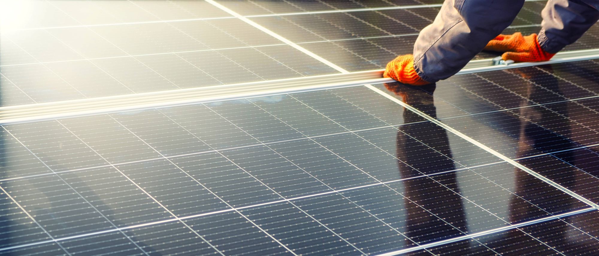 Person's hands in gloves working on rooftop solar panels