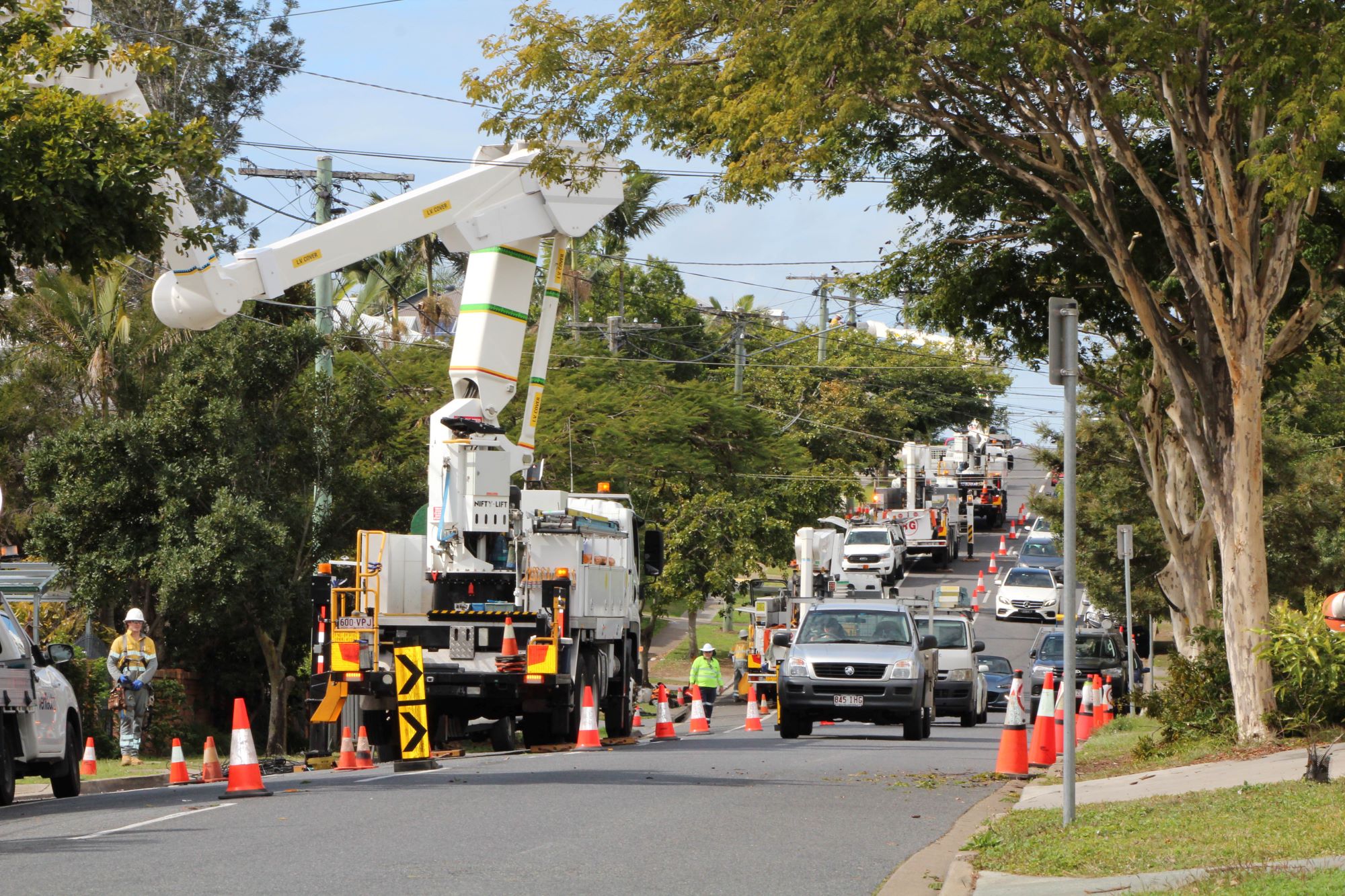 Traffic controllers and cars with multiple work trucks in background