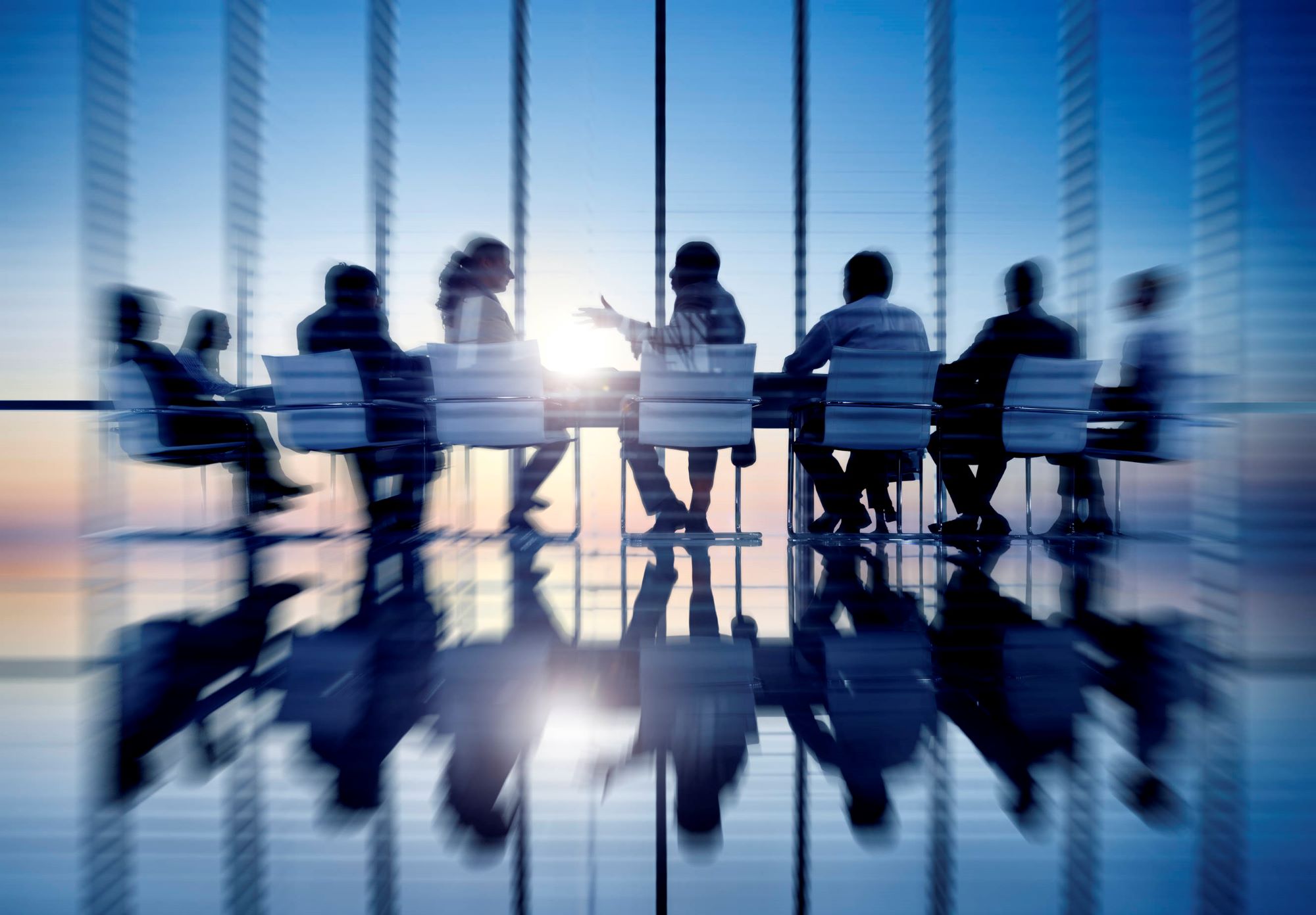 People sitting in chairs in board room talking