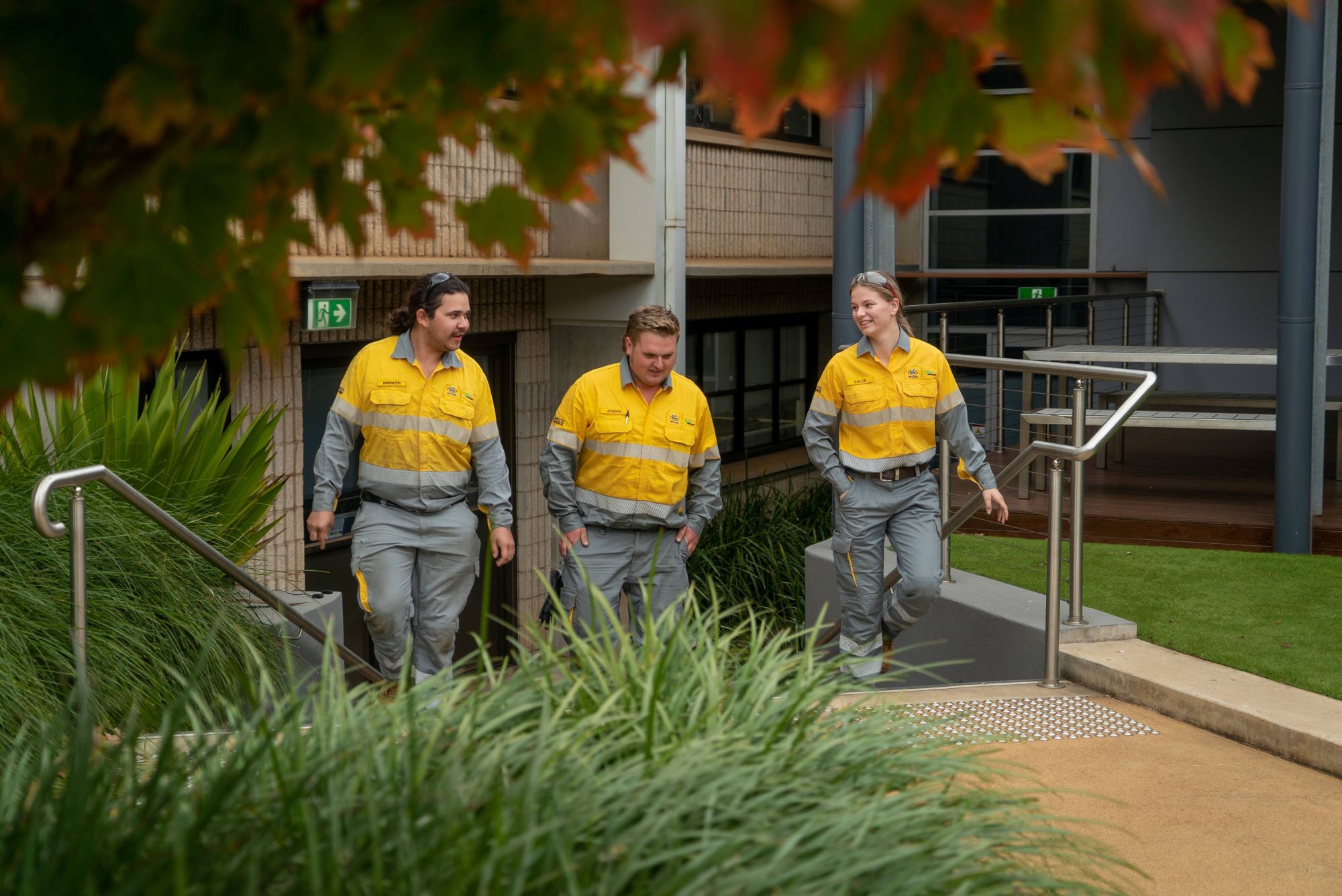 Three crew members walking up stairs in front of a building