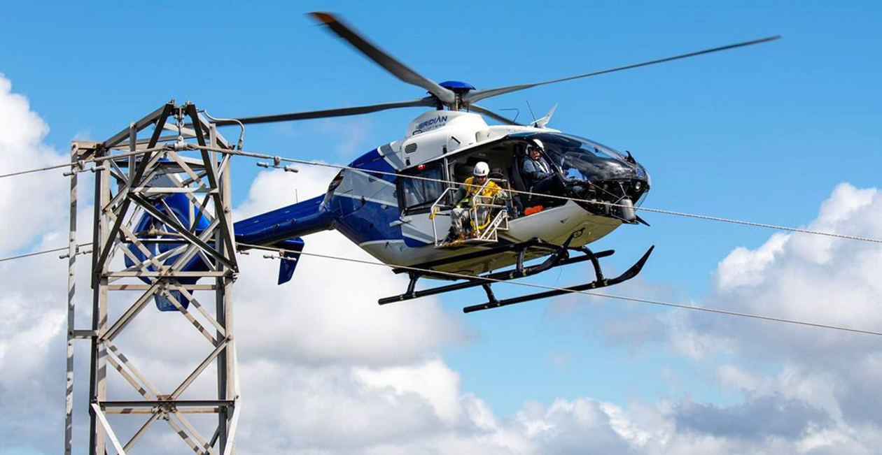 Helicopter hovering over transmission tower